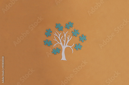 Obraz na płótnie A tree, a crown of blue puzzles on a light brown background. Joint work, project. The result of the interaction. w salonie