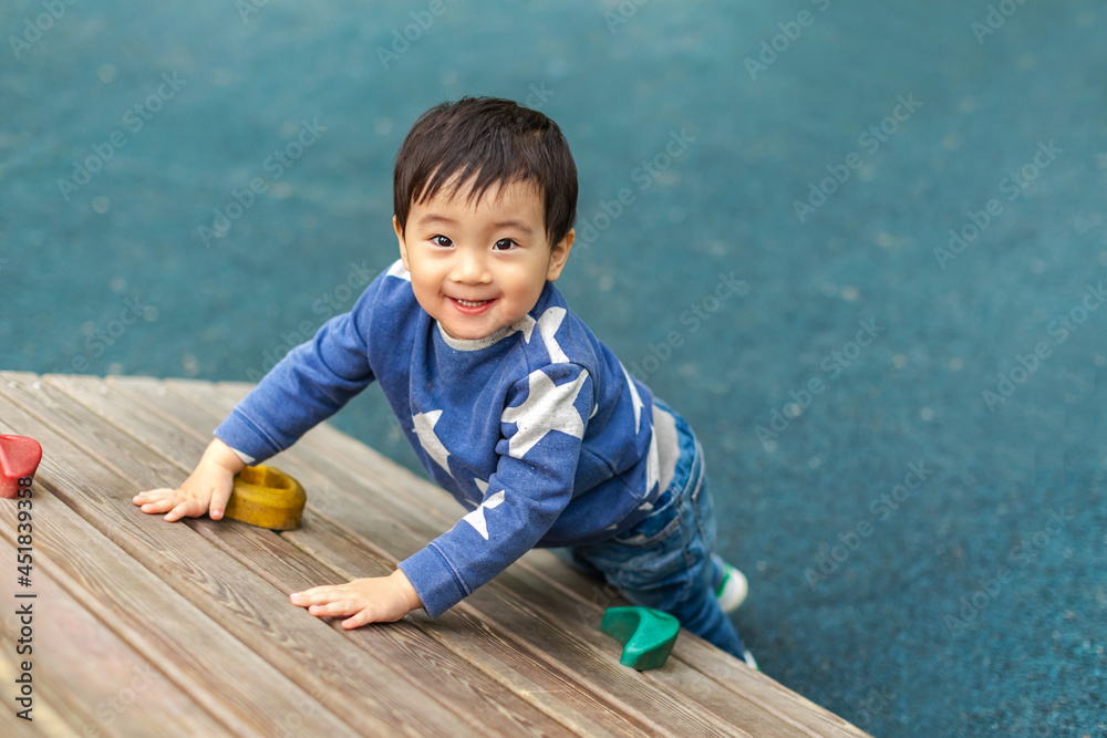 Naklejka premium Asian boy is playing in playground with happy face in summer. Copy space for text