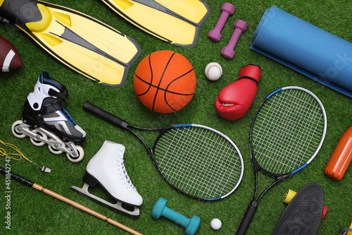 Different sport equipment on green grass  flat lay