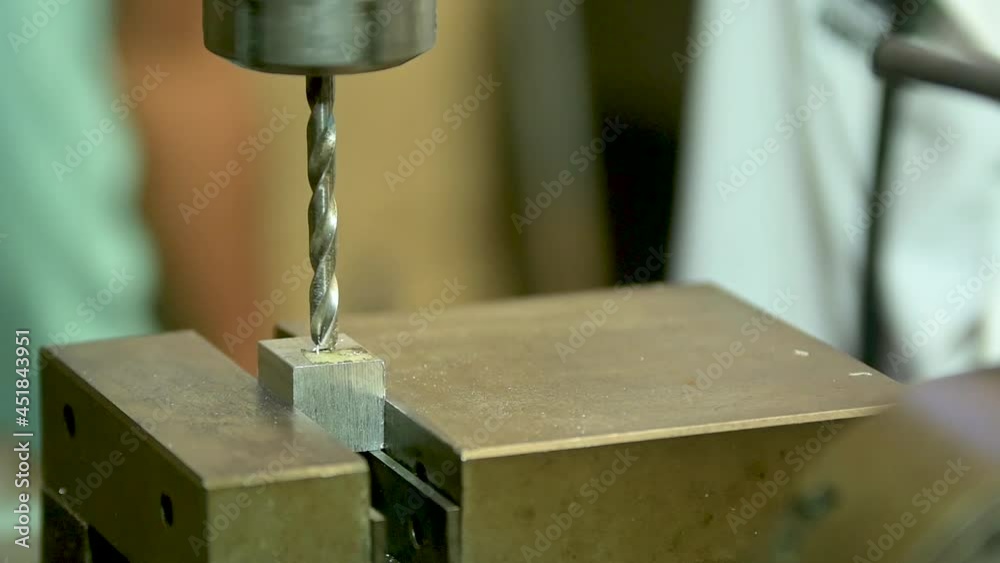 Taladro de mesa haciendo un hueco en un bloque de metal