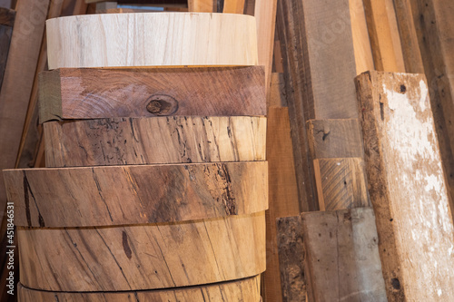 Raw rounds of a variety of wood stacked and waiting to be made into stools photo