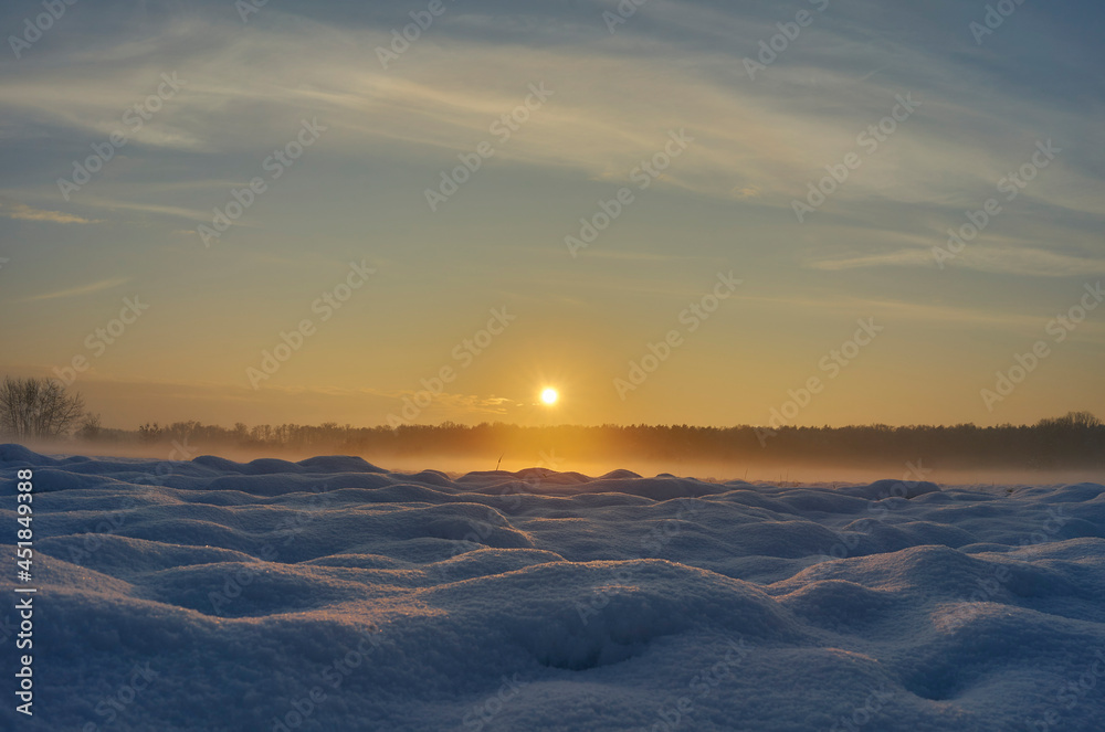 snowy frozen hazy field in the setting winter sun