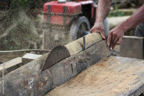 A Timber mill worker cutting tree with saw machine to make wood in sajek, Bangladesh