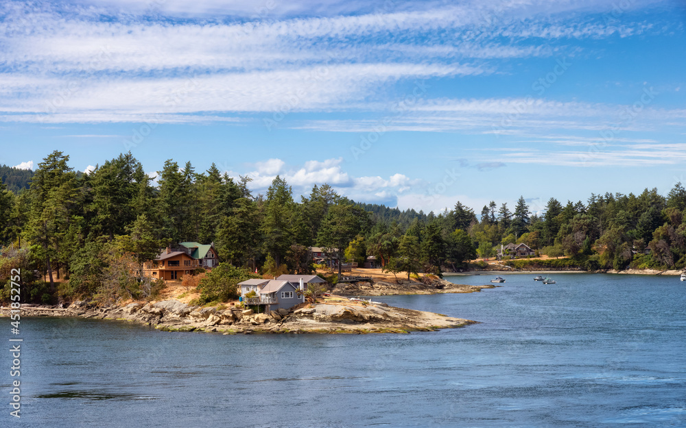 Panoramic View of a Cosy Homes on the rocky coast during a sunny summer day. Taken on Galiano Island near Vancouver Island, BC, Canada.