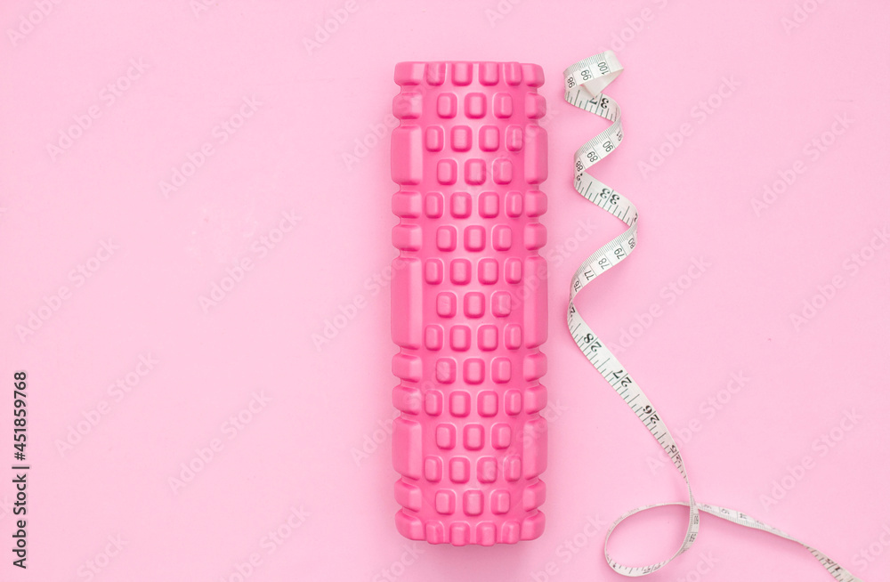 The concept of fitness. Pink fitness roller for training. Centimeter tape. Weight loss. Women's fitness at home. The concept of fitness. Pink fitness roller for training. Centimeter tape. Weight loss. Women's fitness at home.