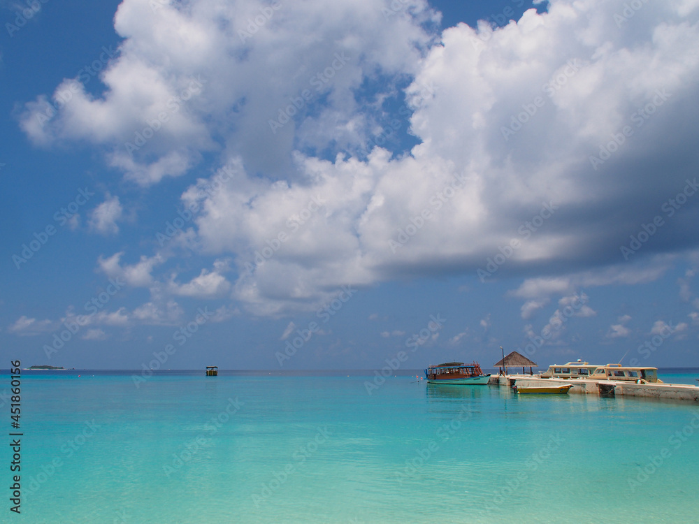 Blue water and blue sky with clouds on the horizon of the Indian Ocean in the Maldives. Copy space for text.