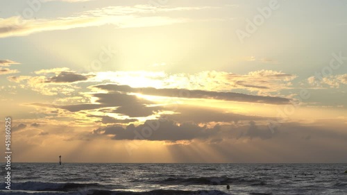 Sun Rays through Clouds Enlight the Sky at Sunset over the Sea photo