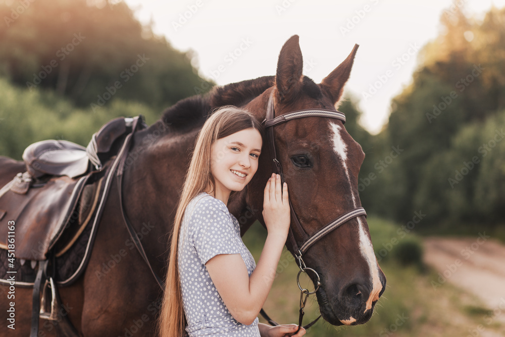 Fototapeta premium Portrait of young girl standing next to a horse looking at camera smiling.