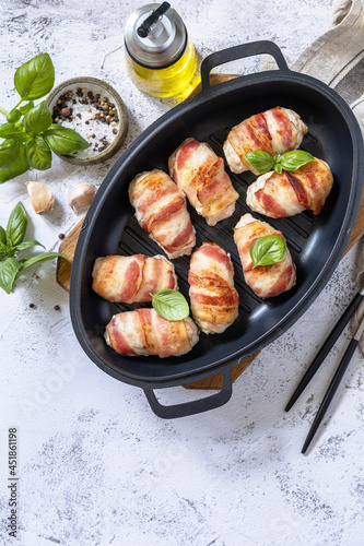 A festive dish. Baked chicken fillet with ricotta in bacon on a stone table top. Top view flat lay background. Copy space.