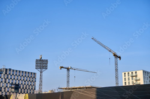 Construction site with cranes and old stadium light structure.  photo