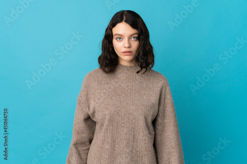 Teenager Ukrainian girl isolated on blue background with sad expression