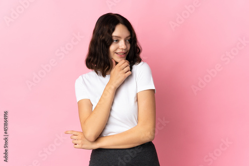 Teenager Ukrainian girl isolated on pink background looking to the side and smiling