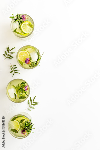 Lemonade with lemon slices and herbs in glasses with lemon reamer