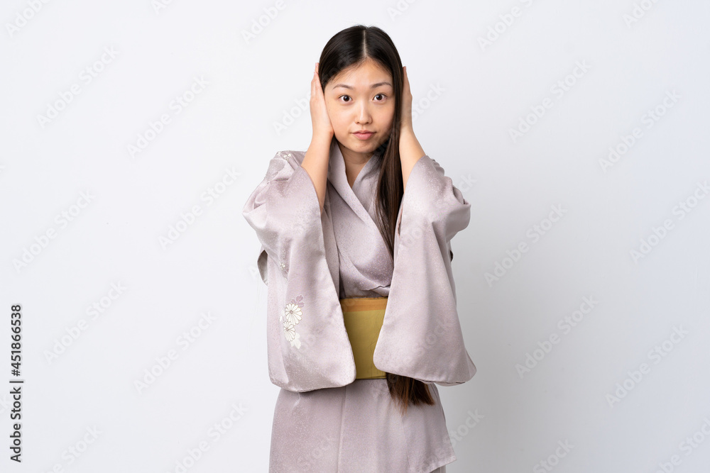 Young Chinese girl wearing kimono over isolated background frustrated and covering ears Young Chinese girl wearing kimono over isolated background frustrated and covering ears