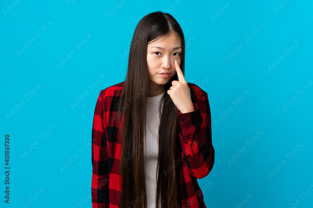 Young Chinese girl over isolated blue background showing something Young Chinese girl over isolated blue background showing something