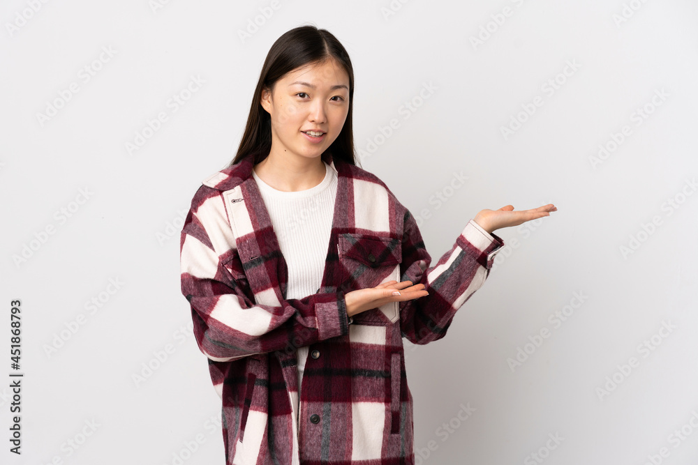 Young Chinese girl over isolated white background extending hands to the side for inviting to come Young Chinese girl over isolated white background extending hands to the side for inviting to come