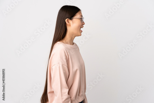 Young Chinese girl over isolated white background laughing in lateral position © luismolinero