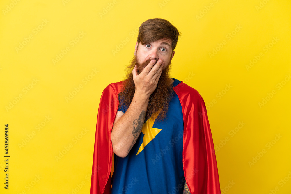 Redhead Super Hero man isolated on yellow background surprised and shocked while looking right Redhead Super Hero man isolated on yellow background surprised and shocked while looking right