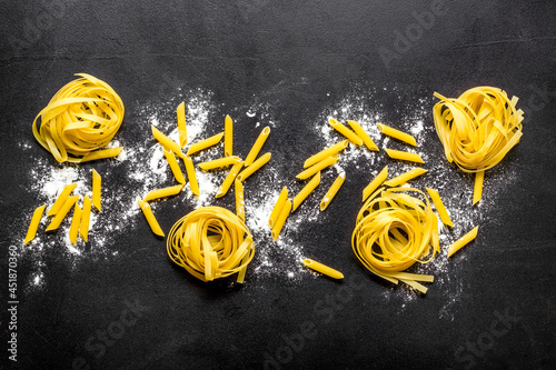 Different tipes of pasta with flour ready for cooking, flat lay photo