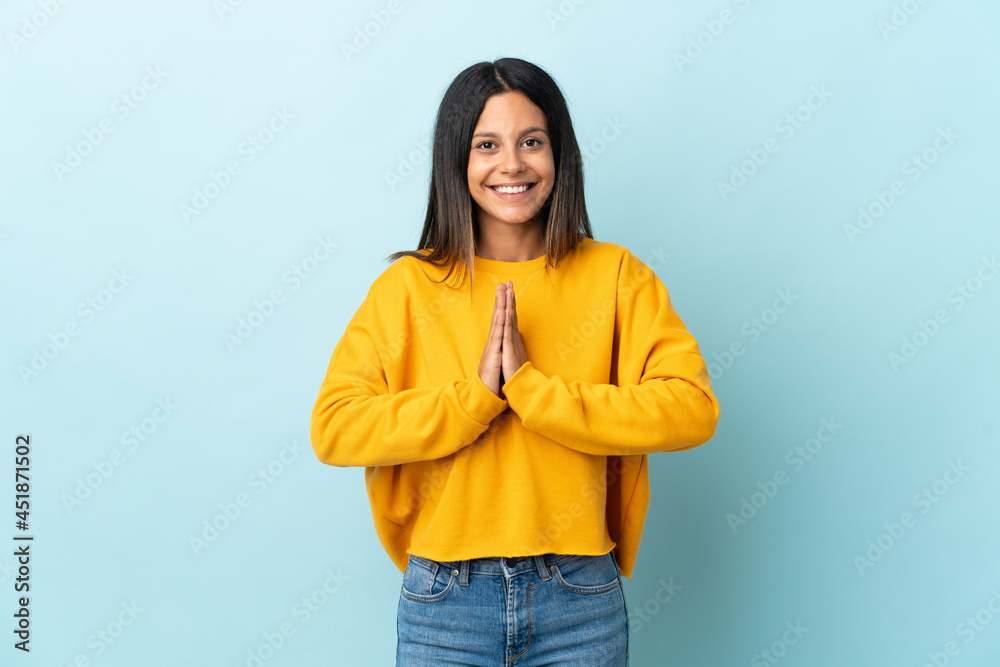 Caucasian girl isolated on blue background keeps palm together. Person asks for something Caucasian girl isolated on blue background keeps palm together. Person asks for something