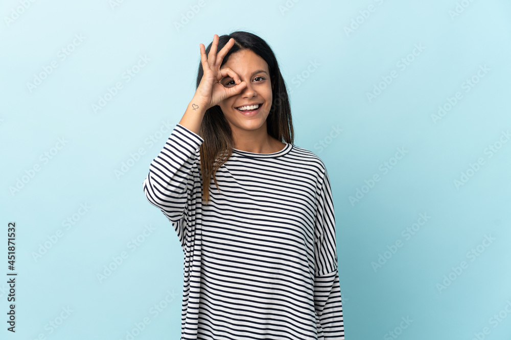 Caucasian girl isolated on blue background showing ok sign with fingers Caucasian girl isolated on blue background showing ok sign with fingers