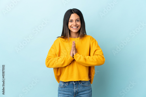 Caucasian girl isolated on blue background keeps palm together. Person asks for something © luismolinero