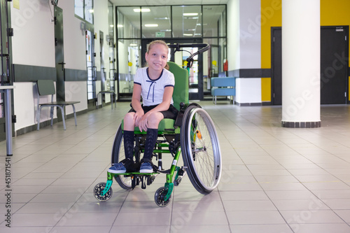 Special child on wheelchair. Girl in school uniform in the school hall.