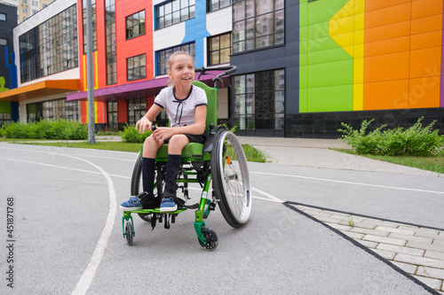 Special child on wheelchair. Girl in school uniform on the background of the school.