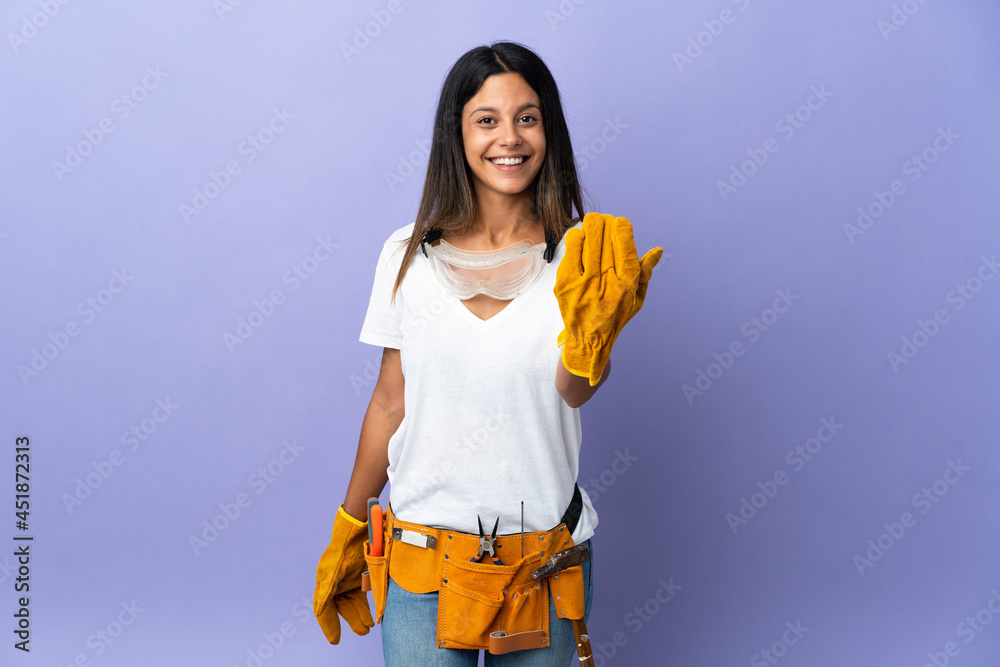 Young electrician woman isolated on purple background inviting to come with hand. Happy that you came