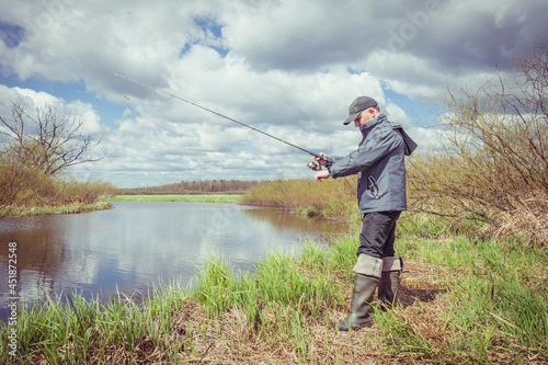Fisherman throws spinning rod on the river bank.