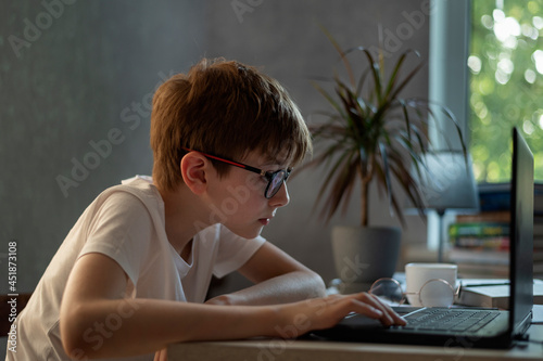 Foto Teenage boy with glasses working with laptop