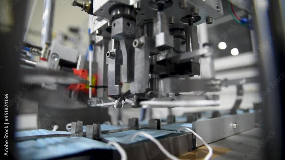Production of medical three-layer blue or white masks. New masks move on a conveyor belt. Making protective masks during the coronavirus pandemic Production of medical three-layer blue or white masks. New masks move on a conveyor belt. Making protective masks during the coronavirus pandemic