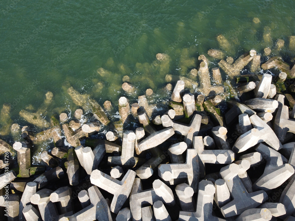 Sea meeting breakwater made out of dolos blocks. Aerial view. Abstract. Pattern. Copy space for text - obrazy, fototapety, plakaty 