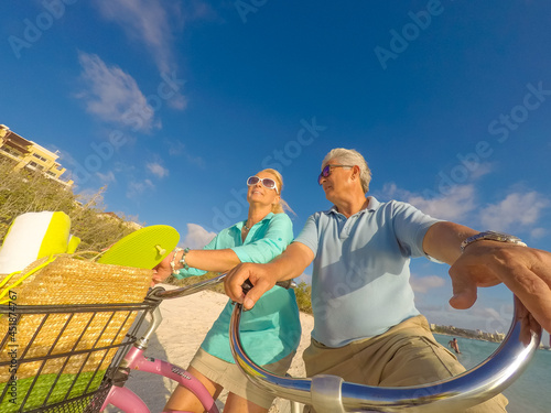 Happy senior couple exercising with bicycles on the beach on a sunny day © TRAVEL EASY
