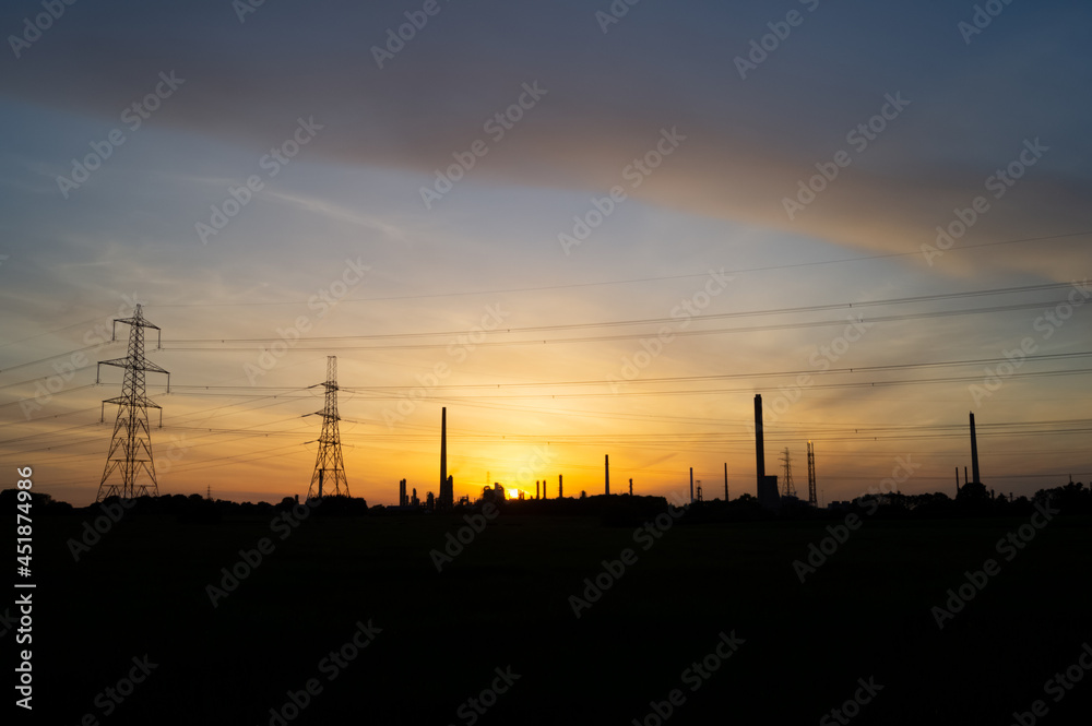 Silhouette of oil refinery and power lines at sunset. Theme or concept. Petrochemicals, fossil fuel, oil, sunset industry. Copy space for text