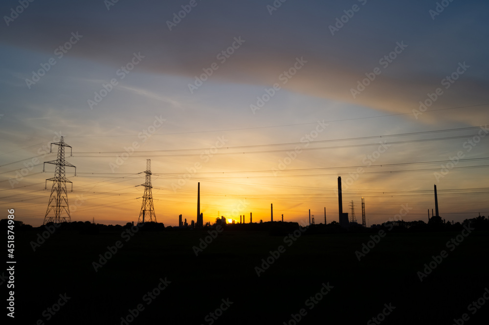 Silhouette of oil refinery and power lines at sunset. Theme or concept. Petrochemicals, fossil fuel, oil, sunset industry. Copy space for text Silhouette of oil refinery and power lines at sunset. Theme or concept. Petrochemicals, fossil fuel, oil, sunset industry. Copy space for text