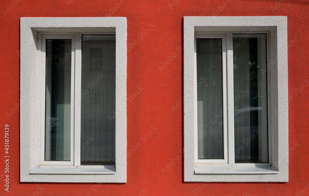 Red wall with two windows with shutters