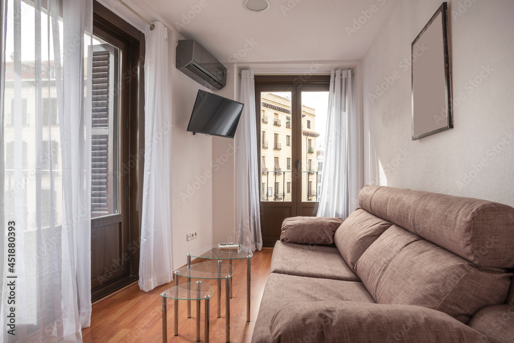 Fototapeta premium Living room with large windows and television in a vacation rental apartment in the center