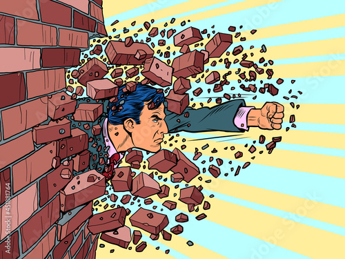 Businessman breaks through a brick wall. The will to overcome obstacles