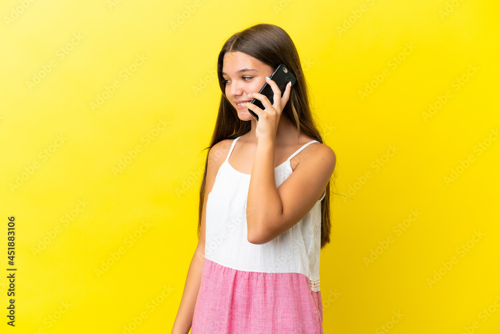 Little caucasian girl isolated on yellow background keeping a conversation with the mobile phone with someone Little caucasian girl isolated on yellow background keeping a conversation with the mobile phone with someone