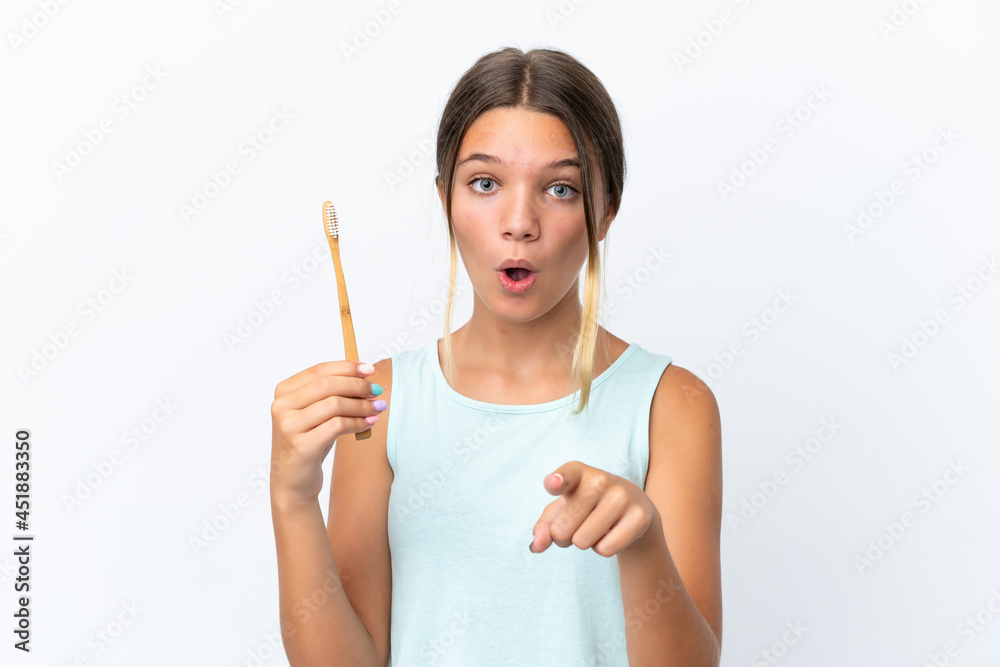 Little caucasian girl holding a toothbrush isolated on white background surprised and pointing front Little caucasian girl holding a toothbrush isolated on white background surprised and pointing front