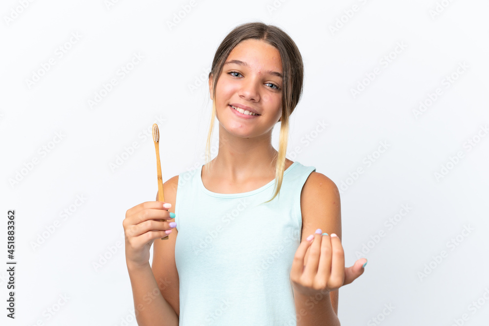 Little caucasian girl holding a toothbrush isolated on white background inviting to come with hand. Happy that you came Little caucasian girl holding a toothbrush isolated on white background inviting to come with hand. Happy that you came