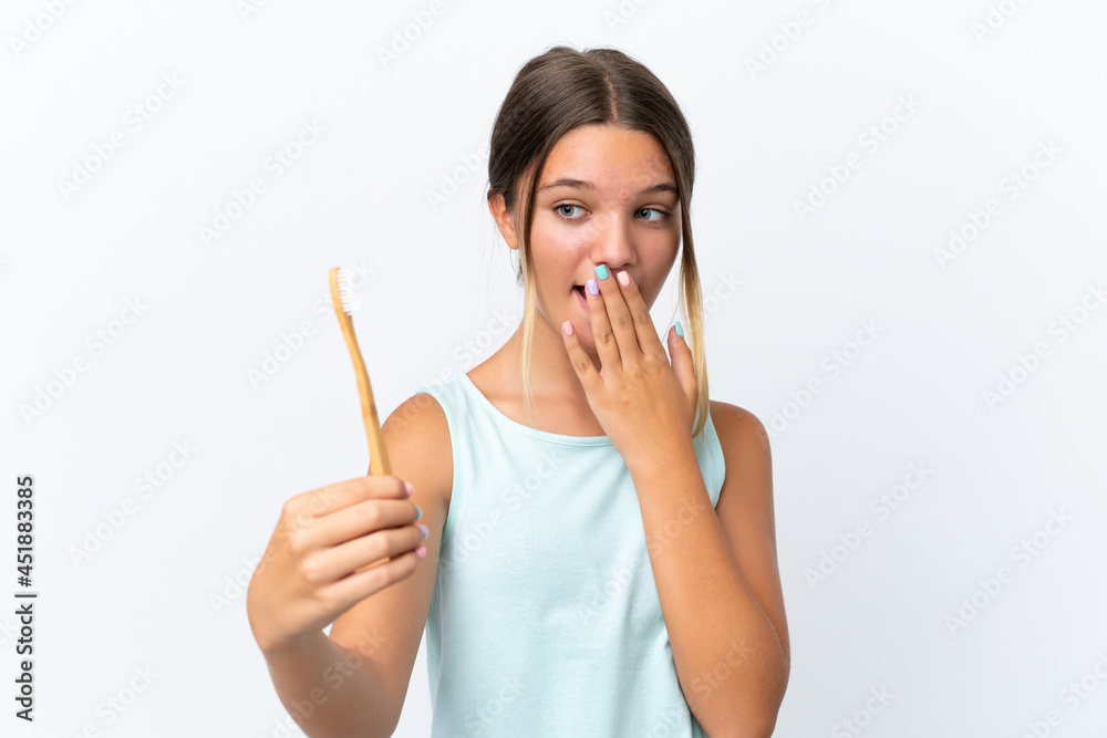 Little caucasian girl holding a toothbrush isolated on white background with surprise and shocked facial expression Little caucasian girl holding a toothbrush isolated on white background with surprise and shocked facial expression