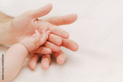 Newborn Baby Hand In Mother and Father Hands on White Blanket. Concept of Parenthood  Child Care. Nursery for Children. Parent Love Concept.