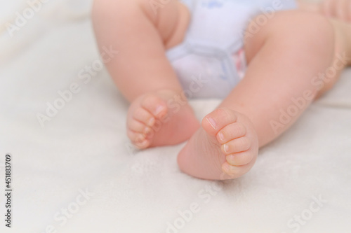 Feet Of Newborn Baby On White Blanket. Text Space. Child Care and Protection or Adoption