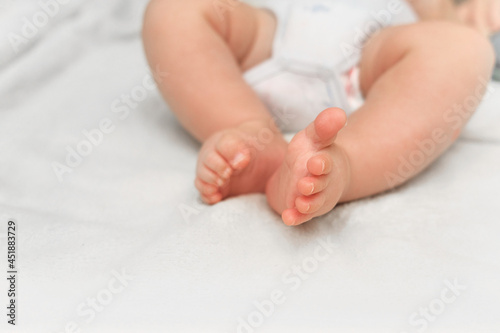Feet Of Newborn Baby On White Blanket. Text Space. Child Care and Protection or Adoption