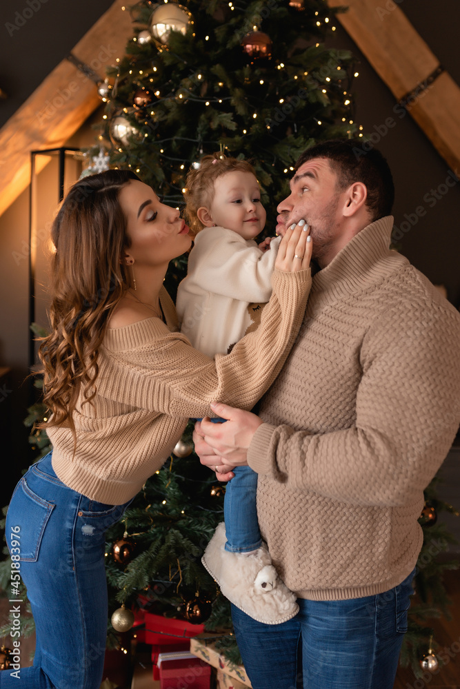 Merry Christmas and Happy Holidays. Happy mom, dad and daughter near the Christmas tree. The morning before Christmas. Close-up portrait of a loving family.