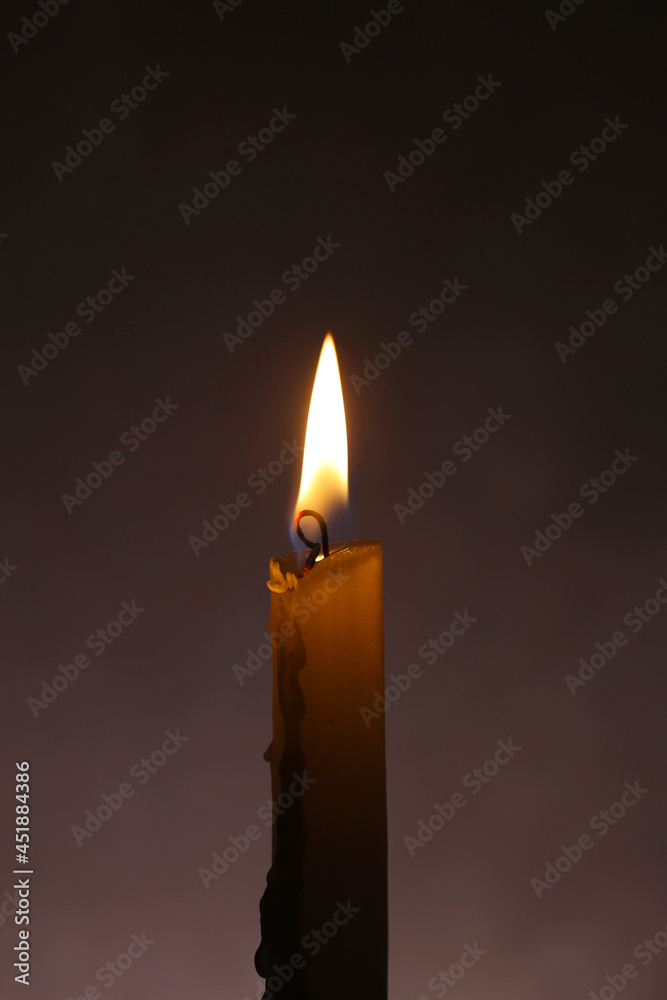 The candle is burning, on a dark background. Macro The candle is burning, on a dark background. Macro