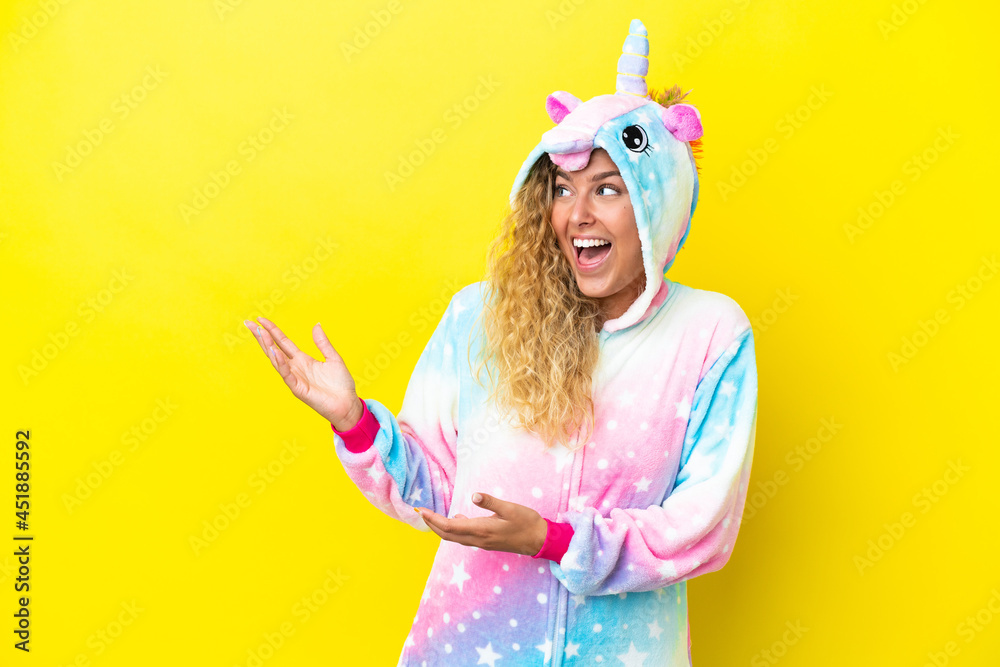 Girl with curly hair wearing a unicorn pajama isolated on yellow background with surprise facial expression Girl with curly hair wearing a unicorn pajama isolated on yellow background with surprise facial expression