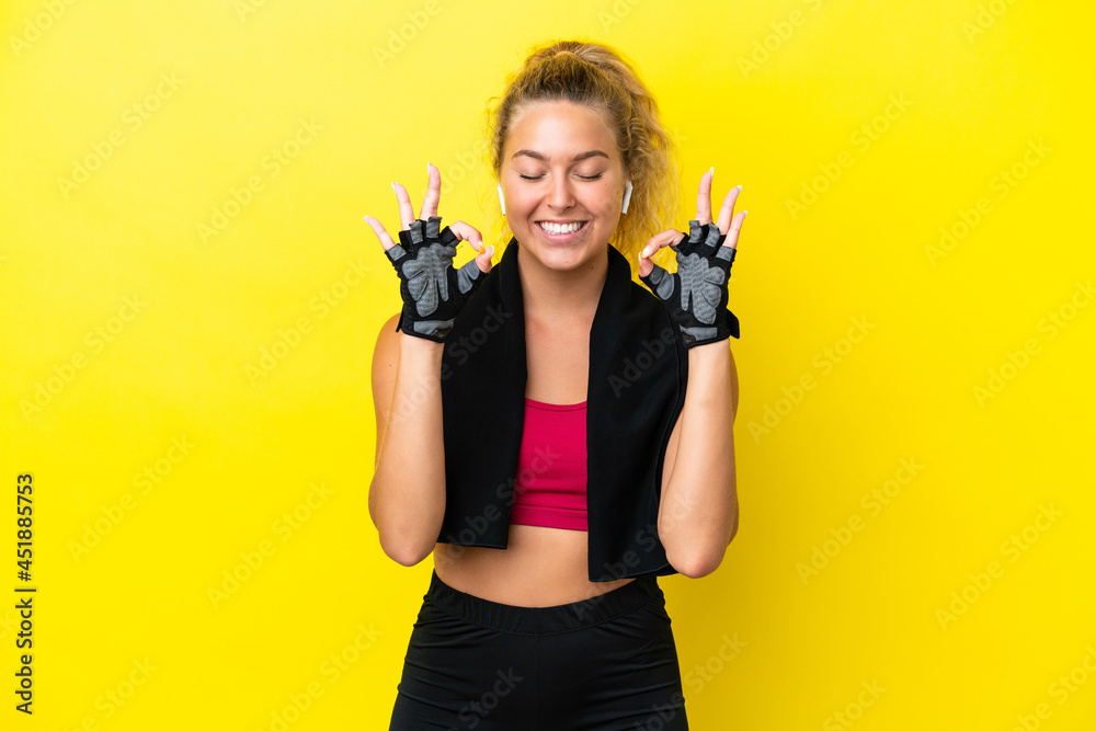Sport woman with towel isolated on yellow background in zen pose Sport woman with towel isolated on yellow background in zen pose